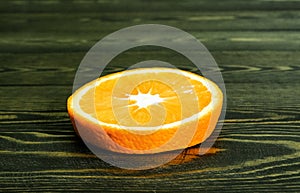 Round slice bright juicy ripe beautiful orange on a coarse dark wooden background from boards