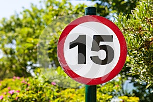 Round speed limit sign fifteen on the background of trees