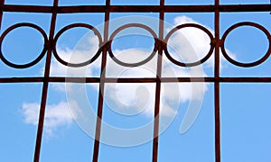 Round steel fence with blue sky and clouds background