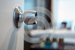 round steel stainless door handle-lock on the open white door to the bathroom. Copy space