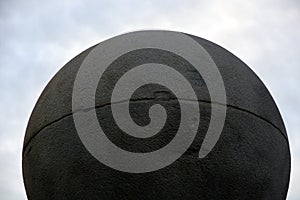 Round stone ball at blue sky with clouds background.