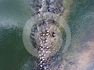 Round stone rocks standing half submerged in the midlle of the Sava river stream photo