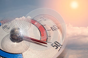 Round street outdoor thermometer with arrow shows extreamly high temperature on hot sunny summer day