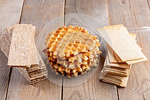 Round sweet calorie waffles and healthy grain crispbreads on  wooden table.