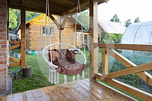 Round swinging chair in the gazebo outdoors. Summer