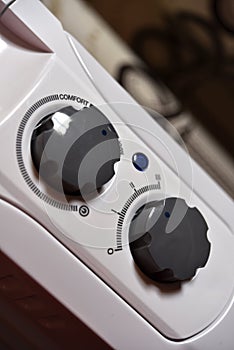 Round switches on a white radiator. The control panel