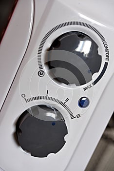 Round switches on a white radiator. The control panel