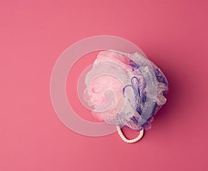 Round synthetic washcloth on a pink background