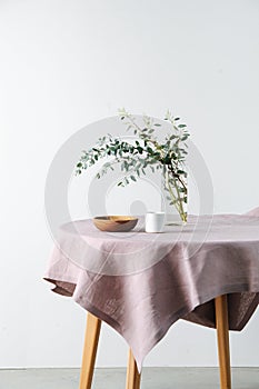 Round table with a rough pale pink tablecloth and branch in a jar