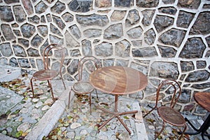 Round table and some chairs standing at stone wall of cafe