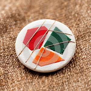 A round textile badge featuring a textured light brown fabric photo