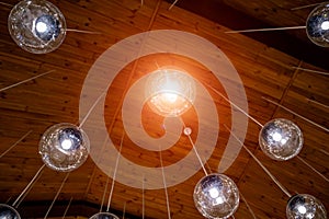 Round transparent bulbs hanging from wooden celling. View from below. Modern interior.