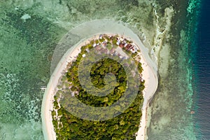 Round tropical island with white sandy beach, top view.A small island surrounded by azure water and coral reefs, a top view