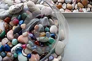 Round vase filled with semi-precious stones next to a box of sea pebbles and shells