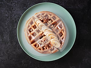 round waffle with banana slice, nuts and icing sugar