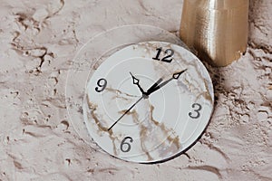 Round wall clock. Clock hands and dial. On the sand.