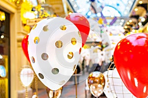 Round white with a golden helium air balloon in the background of a group of red colors. Decorations in the mall, festive window