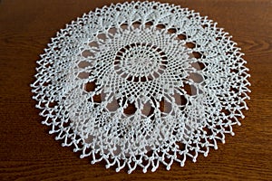 Round white handmade crochet lace doily on wood