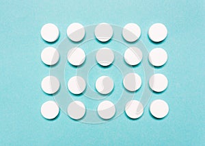 Round, white pills on a blue background. Disease treatment concept, healthcare