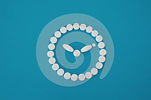 Round white pills clock on blue background