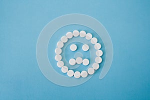 Round white pills sad smile on blue background