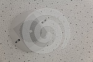 A round white speaker with a mesh is fixed to the white ceiling