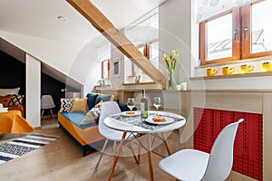 Round white table with wine and glasses in the attic floor apartment.