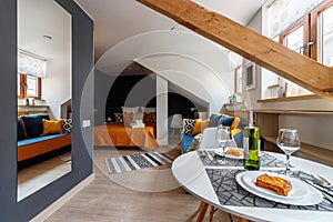 Round white table with wine and glasses in the attic floor apartment.