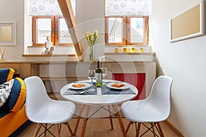 Round white table with wine and glasses in the attic floor apartment.