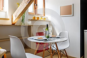 Round white table with wine and glasses in the attic floor apartment.