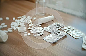 Round white tablets and oval pills on the table with empty boxes and blisters.