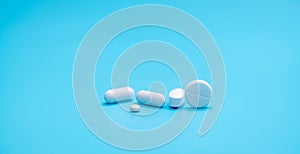 Round white tablets pills on blue background. Tablets and caplets pills pharmaceutical dosage form. Pharmacy and health topics