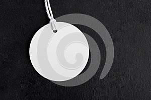 Round white tag mockup with white cord, close up. Blank paper price tag isolated on black background