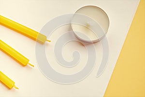 Round white and three yellow candles on white yellow table