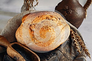 Round white wheat homemade bread. Close-up of white bread with milk and homemade black salt in a wooden ladle. Close-up