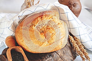 Round white wheat homemade bread. Close-up of white bread with milk and homemade black salt in a wooden ladle. Close-up