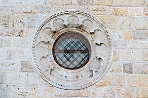 Round window with a black metal fence in an old brick and stone facade