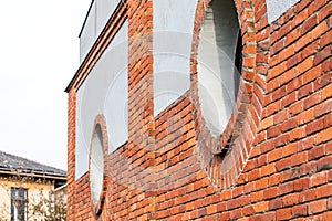 Round window. Red brick wall and light plaster