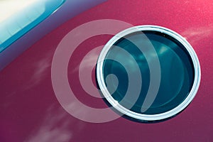 Round window similar to a porthole in crimson car