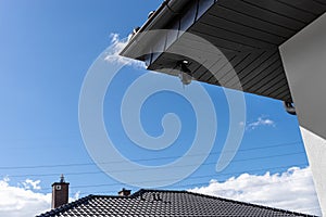 Round wireless camera mounted on the corner of the roof in the soffit, monitoring of a single-family house.