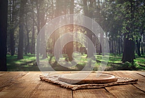 Round wood board on wooden table on forest background