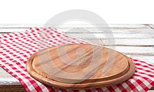 Round wood pizza cutting board and tablecloth on wooden table isolated on white background. Top view and copy space, Empty and