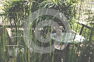 round wood table on terrace of house. wicker rattan chair on pat