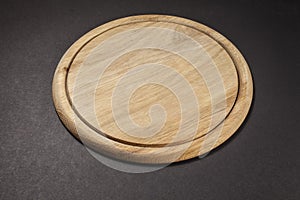 Round wooden breadboard on grey