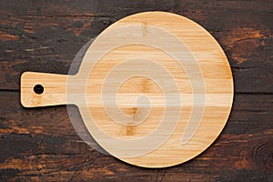 Round wooden cutting board for pizza ondark wooden background. Top view. Mock up for food project photo