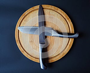 Round wooden cutting board with two crossed knives