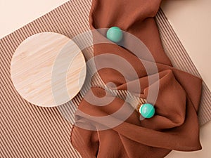 Round wooden mock up on beige corrugated paper background,brown folded wavy fabric,2 turquoise green balls,copy space