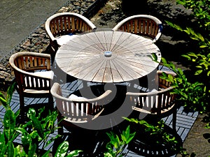 Round wooden patio table with chairs around in aerial view with green branches encroaching into the scene. photo