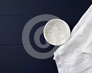 Round wooden plate and white linen towel on blue wooden background