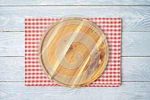 Round wooden tray with red checked tablecloth on rustic wooden table Kitchen, cooking or baking mock up background for design